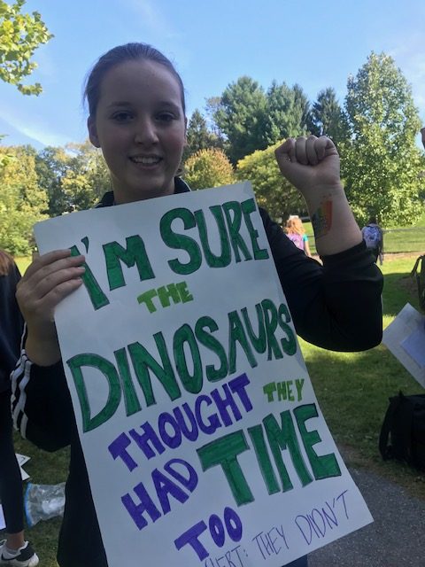 Emily Lyons holding a sign and showing off her strike for the climate temporary tattoo
