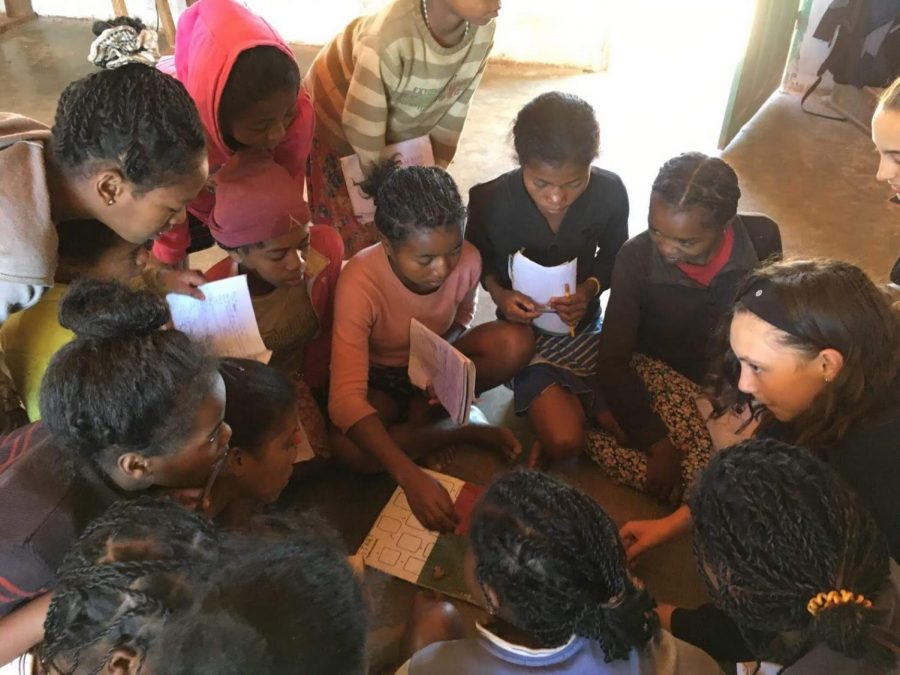 Emma uses a board game to teach numbers and colors in English to students in Madagascar.