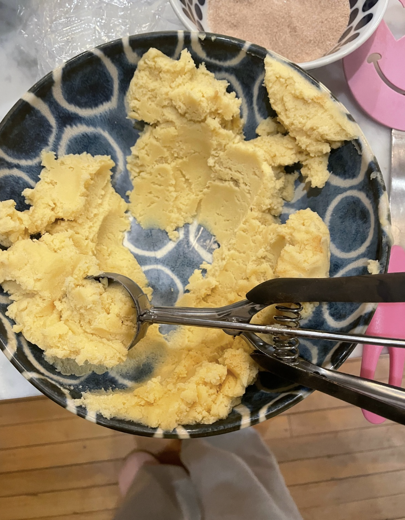 Snickerdoodle dough being scooped and rolled into spheres