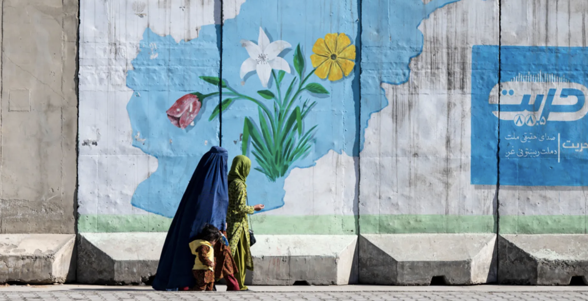 Women and child walking an empty street, dressed in traditional burqas.