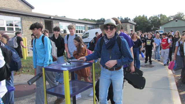 RHS senior Mason Decker uses a magnetic key to unlock his phone from the Yondr pouch at dismissal.