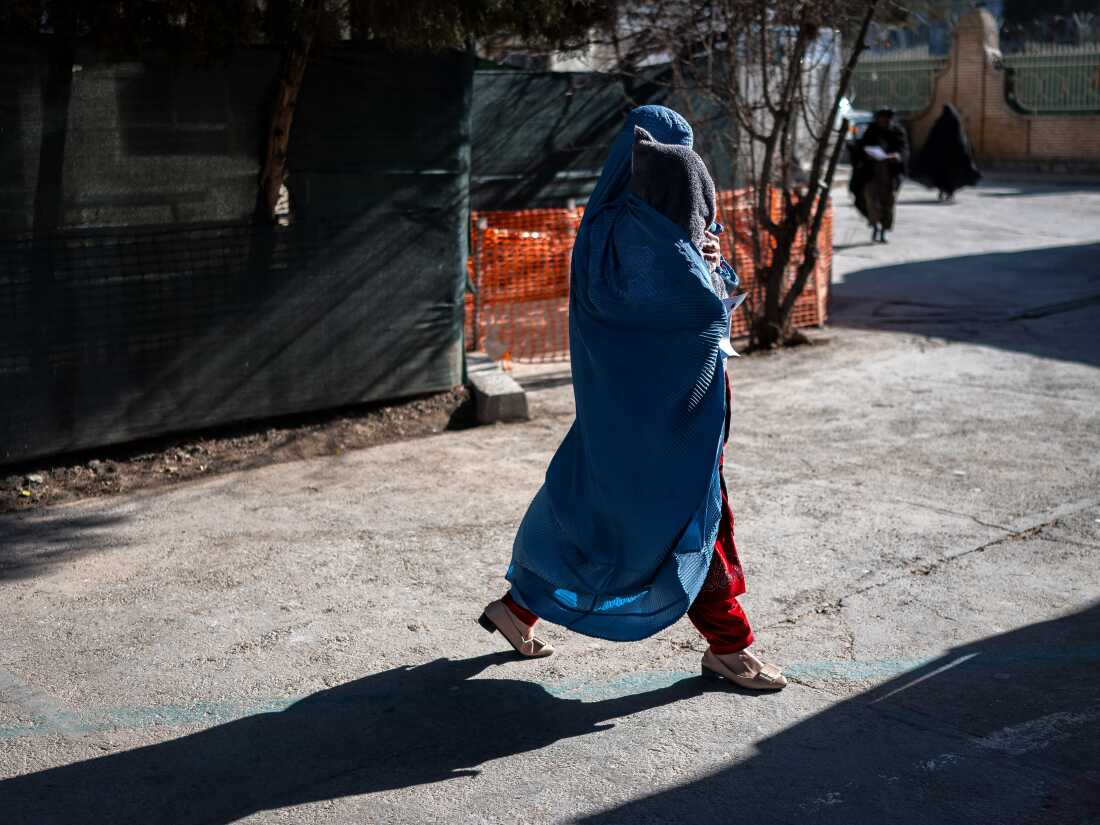This photograph taken on January 8, 2026 shows an Afghan burqa-clad woman walking with her child at the Medecins Sans Frontieres (MSF) centre inside a hospital in Herat. In the country of more than 40 million people, there are relatively few medical centres that can help treat malnutrition. Some families travel hundreds of kilometres (miles) to reach Herat hospital as they lack healthcare facilities in their home provinces. (Photo by Wakil KOHSAR / AFP via Getty Images) / To go with 'Afghanistan-Malnutrition-Children' , FOCUS